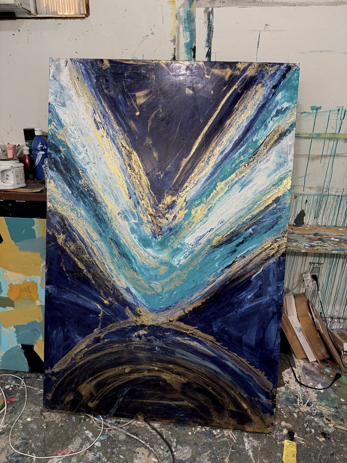 Tall blue, turquoise, and gold abstract painting in the studio.