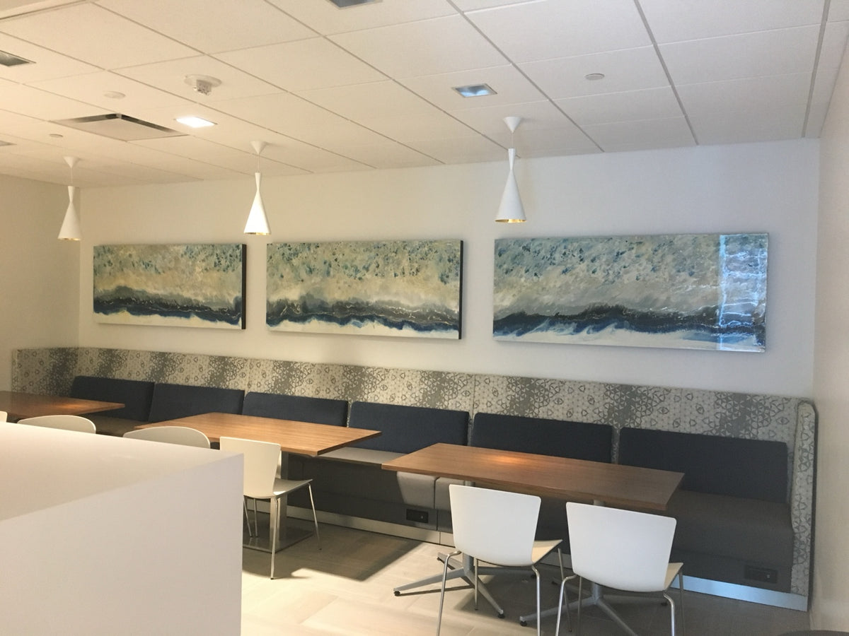 Three blue and cream horizontal paintings above banquette seating.