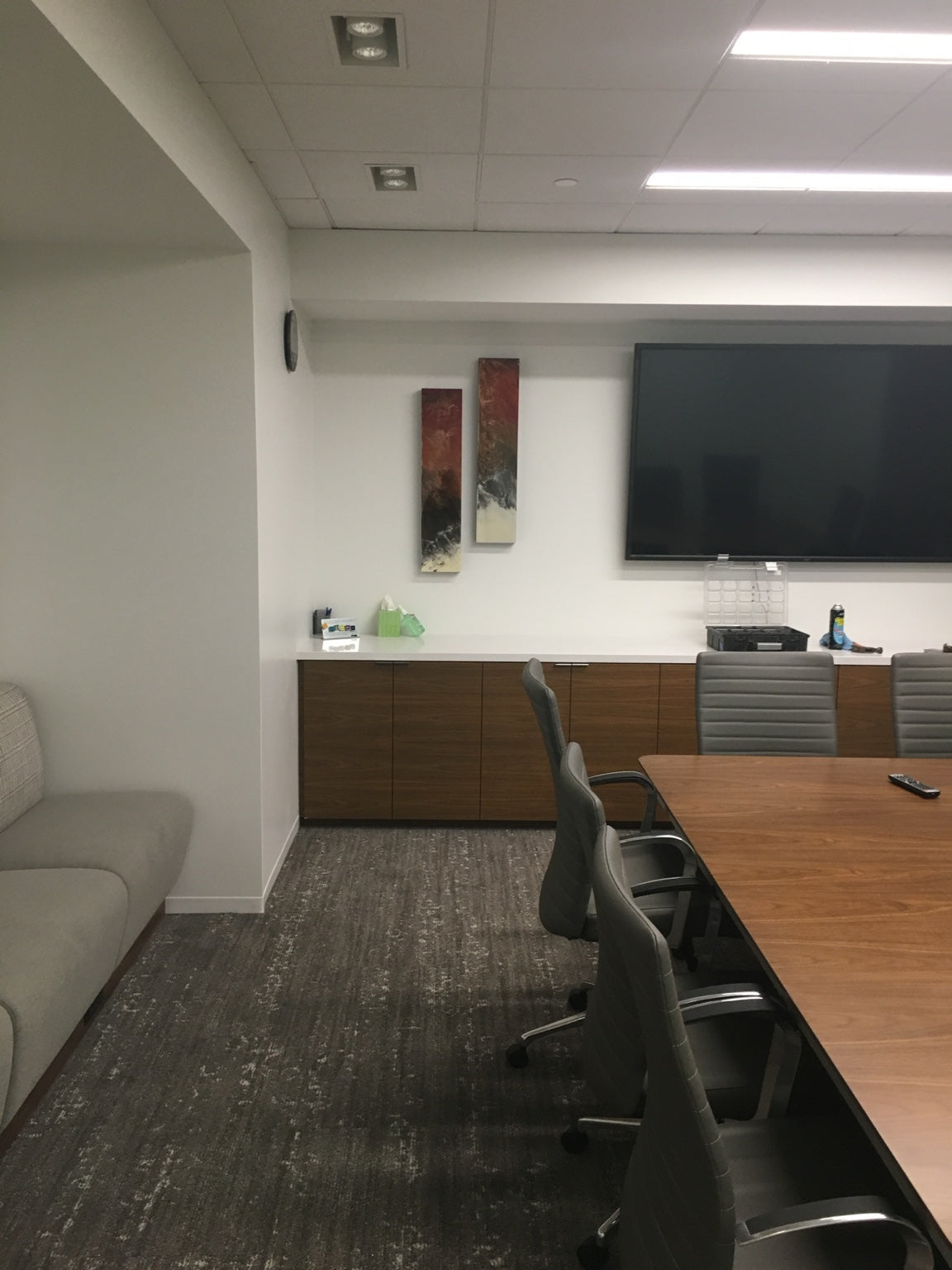 Two slim red and dark abstract panels beside a conference-room screen.