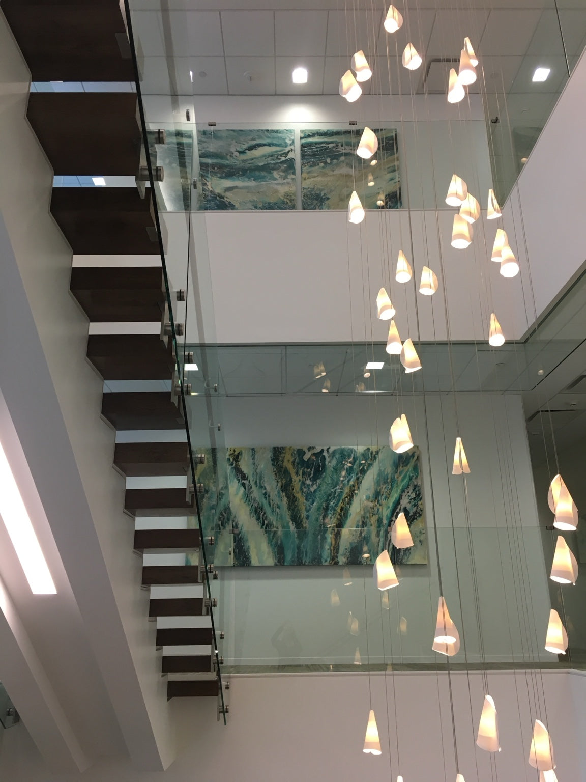 Abstract paintings across multiple floors of a glass stairwell.