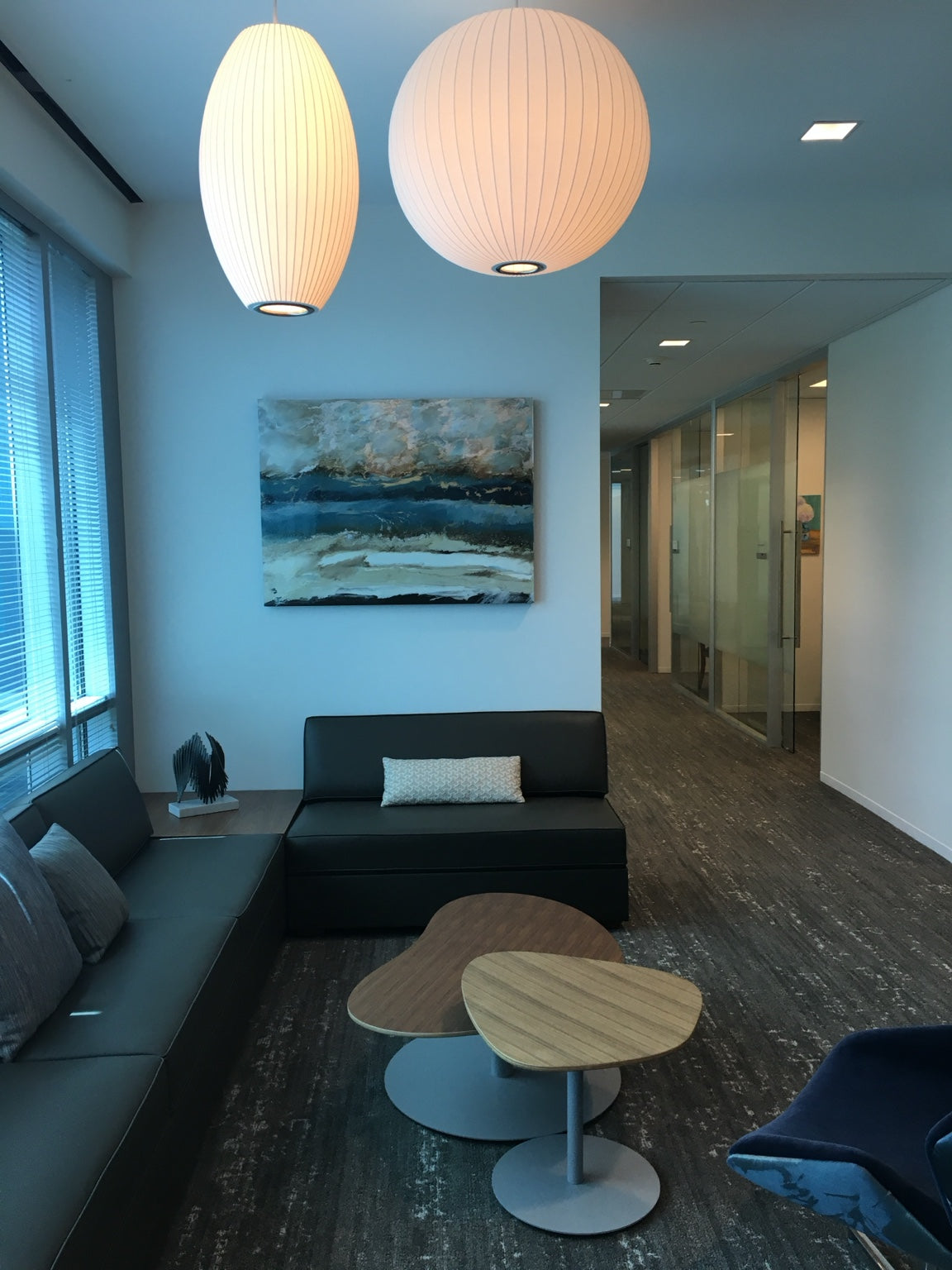 Blue abstract painting above lounge seating in an office.