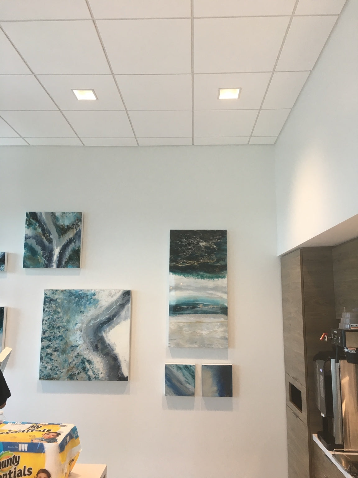 A grouping of differently sized blue and turquoise paintings in a shared interior.