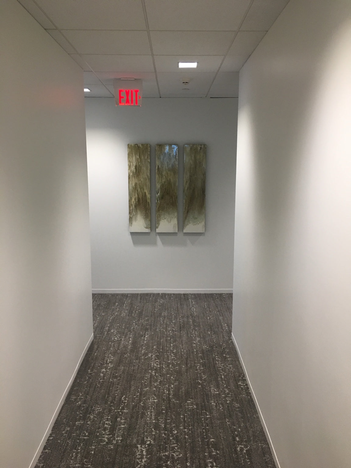 Three slender neutral-toned panels installed at the end of a corridor.