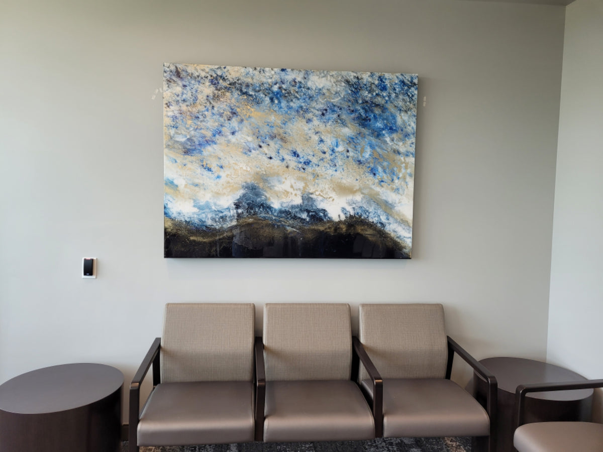 Large blue, gold, and cream abstract painting above three chairs.
